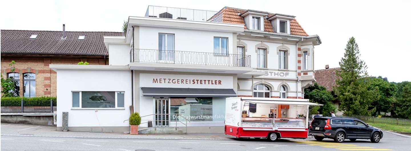 Aussenaufnahme der Metzgerei Stettler in Schüpfen mit dem Märit Bern Verkaufanhänger und dem Zugfahrzeug Volvo.